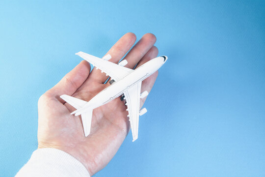 Airplane model in hand on a blue background. Travel concept.