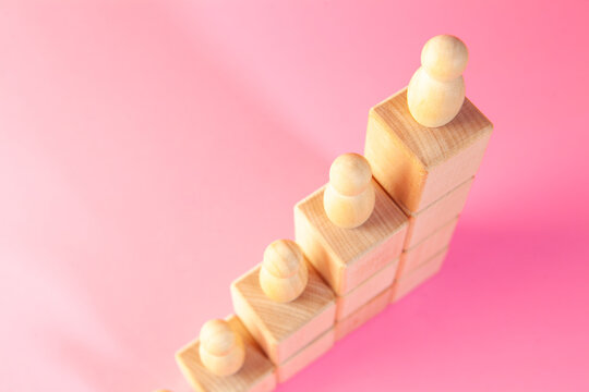 Wooden toy blocks on a pink background. The concept of career growth.