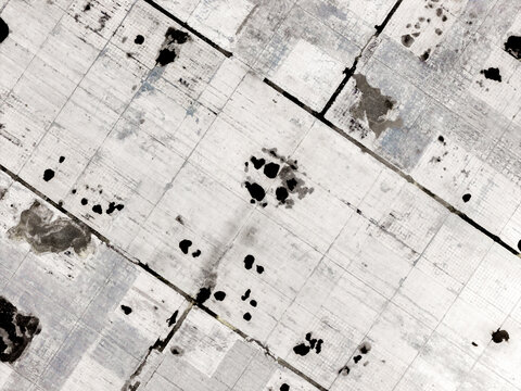Aerial view of the parking lot with a grid pattern of roads and dark patches in Warsaw, Masovian Voivodeship, Poland.