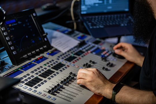 Sound engineer man using mixing console for music production. Professional audio equipment in recording studio.