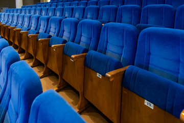 Obraz premium Rows of empty blue seats in a cinema hall. Comfortable velvet chairs for viewers inside an auditorium. Interior of a theate