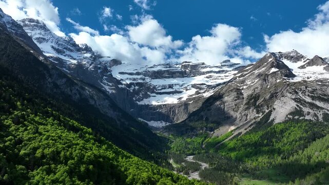 Cirque de Gavarnie glacial amphitheatre with snowy cliffs and green forest valley under blue sky