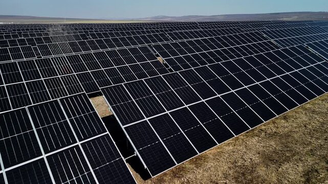 Solar panel installation in a vast field showcasing rows of photovoltaic modules under clear blue skies, highlighting renewable energy technology in a rural landscape
