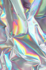 Obraz premium Iridescent crumpled foil abstract background shows rainbow reflections, metallic folds, and glossy texture in a close-up vertical composition.