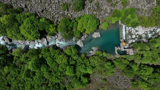 Aerial top-down view of small hydroelectric dam and weir on turquoise Pyrenees river