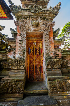 Ornate stone temple door with gold leaf details in Ubud
