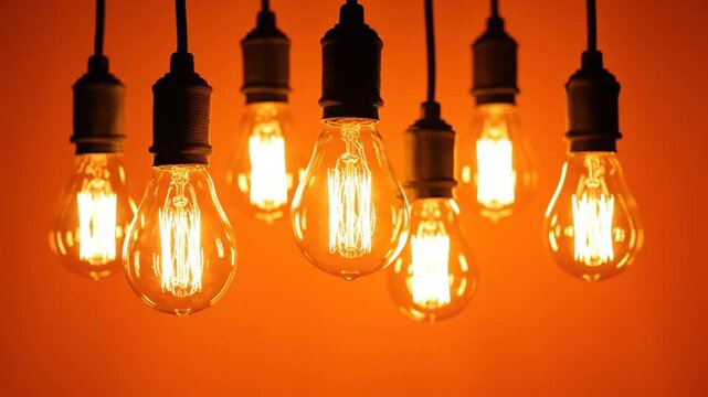 Decorative hanging light bulbs with glowing filaments against a warm orange background