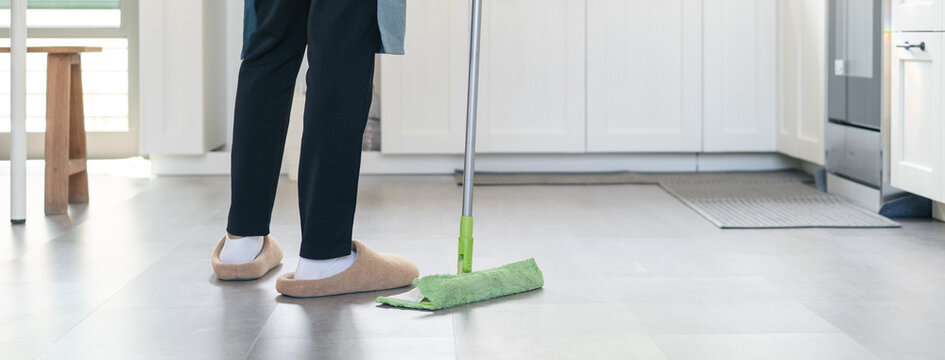 The housewife wipes the wet floor and clean the kitchen.