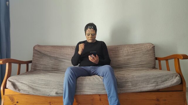 Frankenstein monster celebrating a victory on smartphone