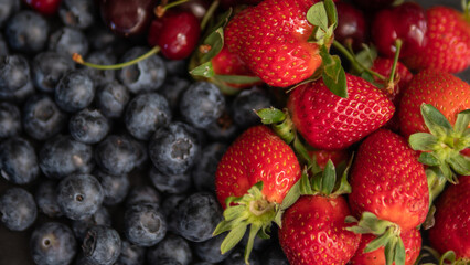 Obraz premium Fresh strawberries and blueberries close up background with ripe summer berries