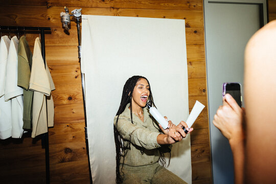 Young woman smiling while holding skin care products and posing for a photo