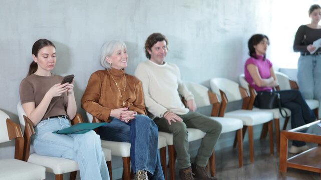 Multiethnic men and women waiting for their appointment while sitting in a bright corridor