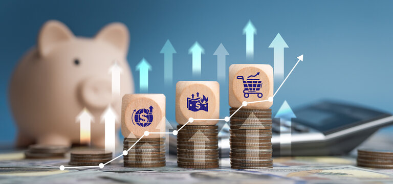 The image depicts soaring living costs and expensive goods. One hand is placing a block onto a wooden coin bearing an icon, and a graph shows rising inflation and an economic crisis.