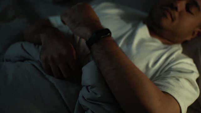 Man sleeping peacefully while wearing a smart watch for sleep tracking. Deep sleep monitoring wearable technology, Recovery wellness, healthy lifestyle and longevity concept.
