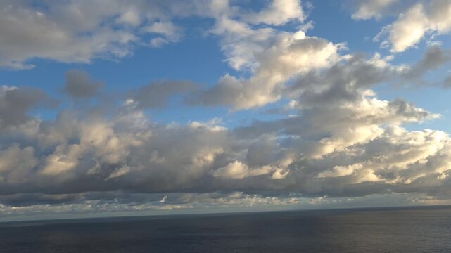 Clouds ocean sky, fluffy white and grey clouds float over the vast blue ocean surface, beautiful serene seascape with changing weather