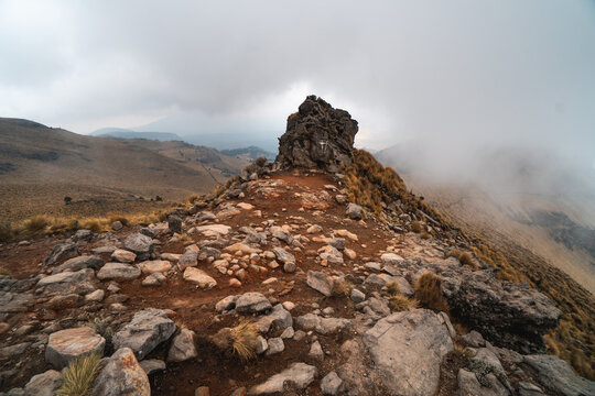 Rocky mountain trail on Popocat&eacute;petl volcano in Mexico with misty atmosphere and rugged terrain during daytime hiking adventure
