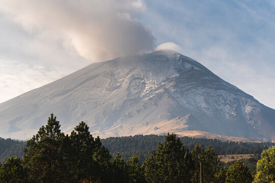 Majestic view of Popocat&eacute;petl volcano in Mexico with smoke rising above forested landscape during daytime in autumn perfect for travel and adventure enthusiasts