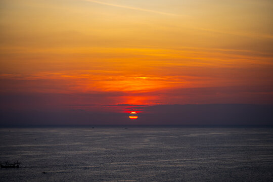 Sunset over the Indian Ocean with traditional fishing boats on the horizon
