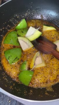 Footage of homemade achar mango pickle making with raw mango cut pieces for making aam achar. Closeup of  cutting ripe Mango for making Pickle with vegetable cutter. A sprinkling of spicy Masala. 