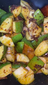 Footage of homemade achar mango pickle making with raw mango cut pieces for making aam achar. Closeup of  cutting ripe Mango for making Pickle with vegetable cutter. A sprinkling of spicy Masala. 