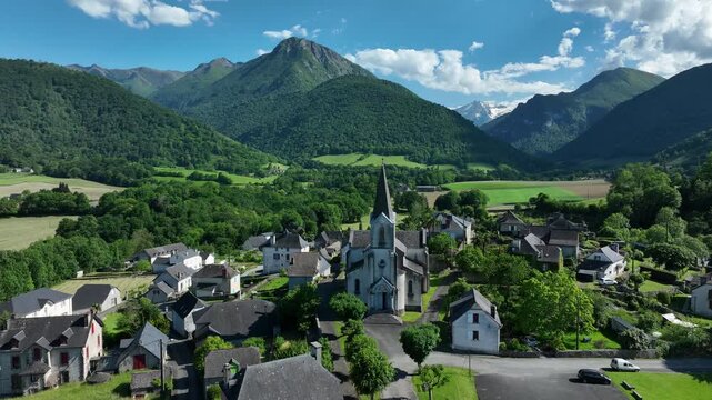 Pyrenees mountain village with church spire in green valley below forested peaks