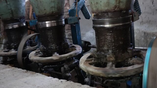 Industrial mortar and pestle grinding seeds for oil extraction