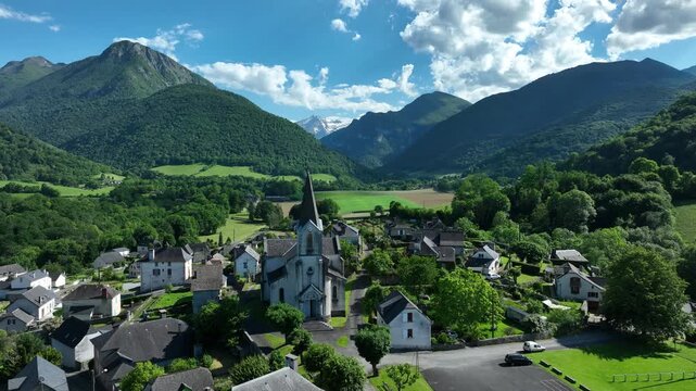 Pyrenees mountain village with old church spire in green valley below forested peaks
