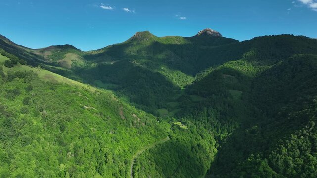 Green forested Pyrenees valley with rocky peaks and mountain road near Col de Spandelles