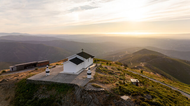 Aerial view of Capela da Senhora das Necessidades do Monte do Colcurinho, a white chapel on a mountain peak overlooking rolling hills at sunset Aldeia das Dez, Coimbra, Portugal.
