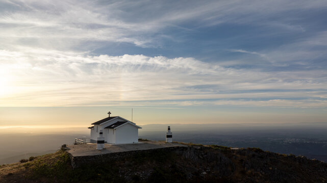 Aerial view of Capela da Senhora das Necessidades do Monte do Colcurinho on a mountain peak under a golden sunset sky in Aldeia das Dez, Coimbra, Portugal.