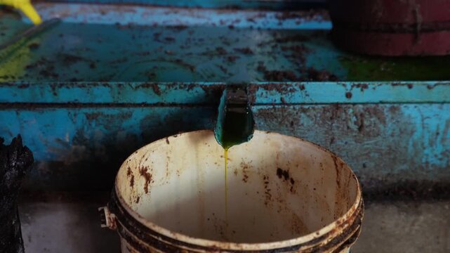 Mustard oil flowing from ghani pipe into bucket
