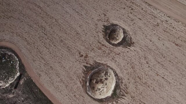 Drone footage showing multiple sinkholes in a dry rural landscape. Natural ground collapse, karst terrain, geological formations, and barren farmland captured from above.