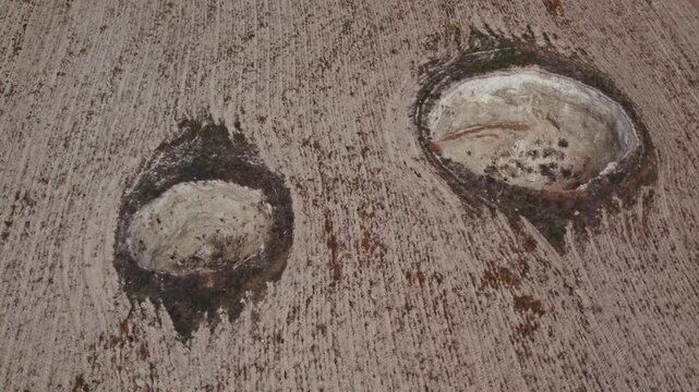 Drone footage showing multiple sinkholes in a dry rural landscape. Natural ground collapse, karst terrain, geological formations, and barren farmland captured from above.
