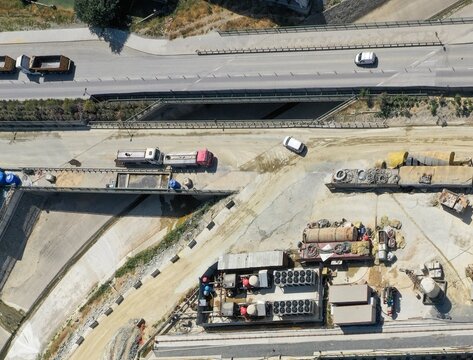 Aerial view of a construction site with industrial machinery, parked trucks, and a highway overpass in Avcilar, Istanbul, Turkiye.