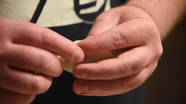 Close-up view of male hands skillfully preparing traditional japanese gyoza. The chef is carefully folding and crimping the dough wrapper