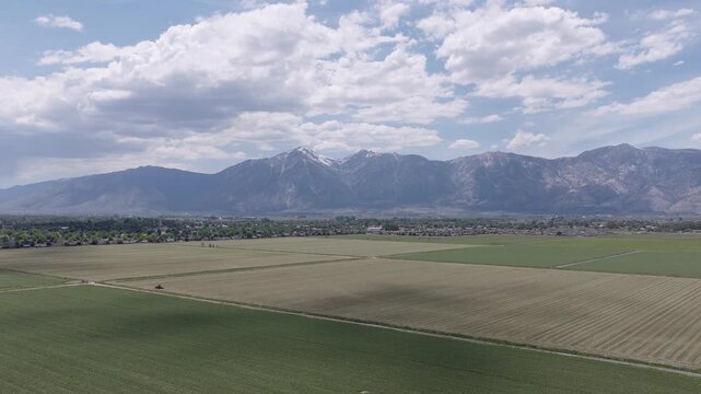 Expansive agricultural fields stretching towards the town of Minden, Nevada, with the majestic, snow-dusted Sierra Nevada mountain range rising under a partly cloudy sky