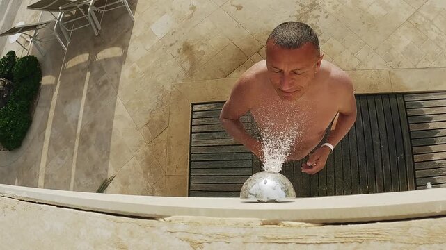 Man standing under an outdoor shower enjoying the refreshing water on a sunny day