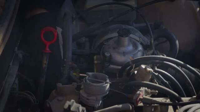 A mechanic adjusts the carburetor on a classic car engine during maintenance. Close-up of hands-on tuning, mechanical repair and vintage vehicle servicing.