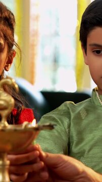 Closeup of Happy Indian Family of Four in Traditional Attire Lighting Diya or Samai Together on Hindu Festival Day at home