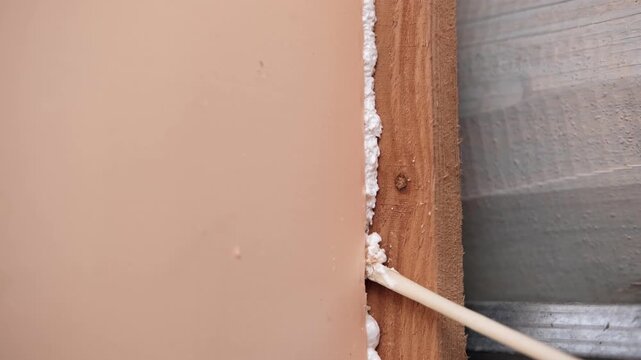 Applying thermal insulation foam with a gun. Using polyurethane foam along wall joints. Expanding the material. Sealing joints and soundproofing walls. Interior renovation. Close-up. Copy space.