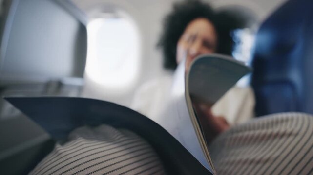 Happy traveler woman reading catalog during a flight in comfortable airplane seating