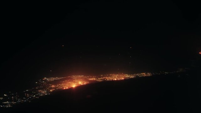 Aerial view from plane flight of city in Kuwait with glowing oil plant fires and lights at night