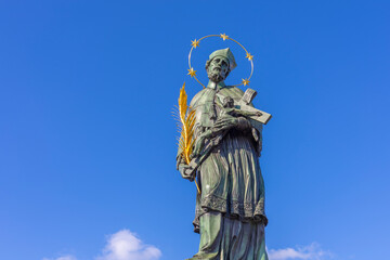 Fototapeta premium Low-angle view of the historic Statue of Saint John of Nepomuk on Charles Bridge against a clear blue sky.
