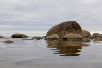 Fototapeta premium Calm Rocky Seascape With Reflections on Shallow Shore Under Overcast Sky