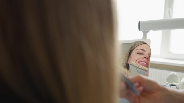 Dentist selecting veneer shade for woman during dental appointment in clinic. Concept of cosmetic dentistry and smile makeover.