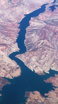 Breathtaking aerial view of sprawling water dam reservoir on Euphrates rive nestled amid rugged, mountainous terrain in Turkey, vertical video