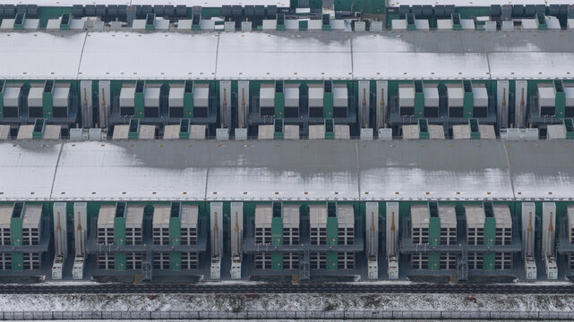 Aerial view of a large industrial data center facility with rows of cooling units and snow-covered rooftops in Middenmeer, North Holland, Netherlands.