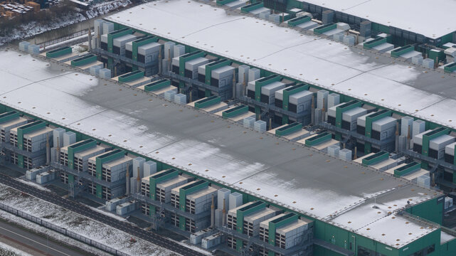 Aerial view of a large modern data center facility with green modular cooling units and snow-covered roofs Middenmeer, North Holland, Netherlands.