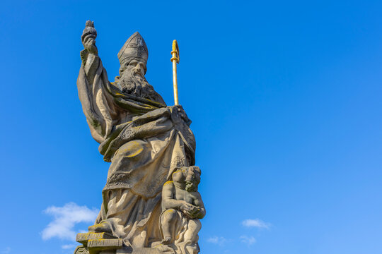 Low angle view of the historic Statue of Saint Augustine of Hippo holding a burning heart on Charles Bridge, Prague.