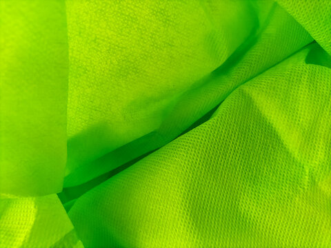 Abstract macro background of lime green non-woven polypropylene reusable bag fabric.